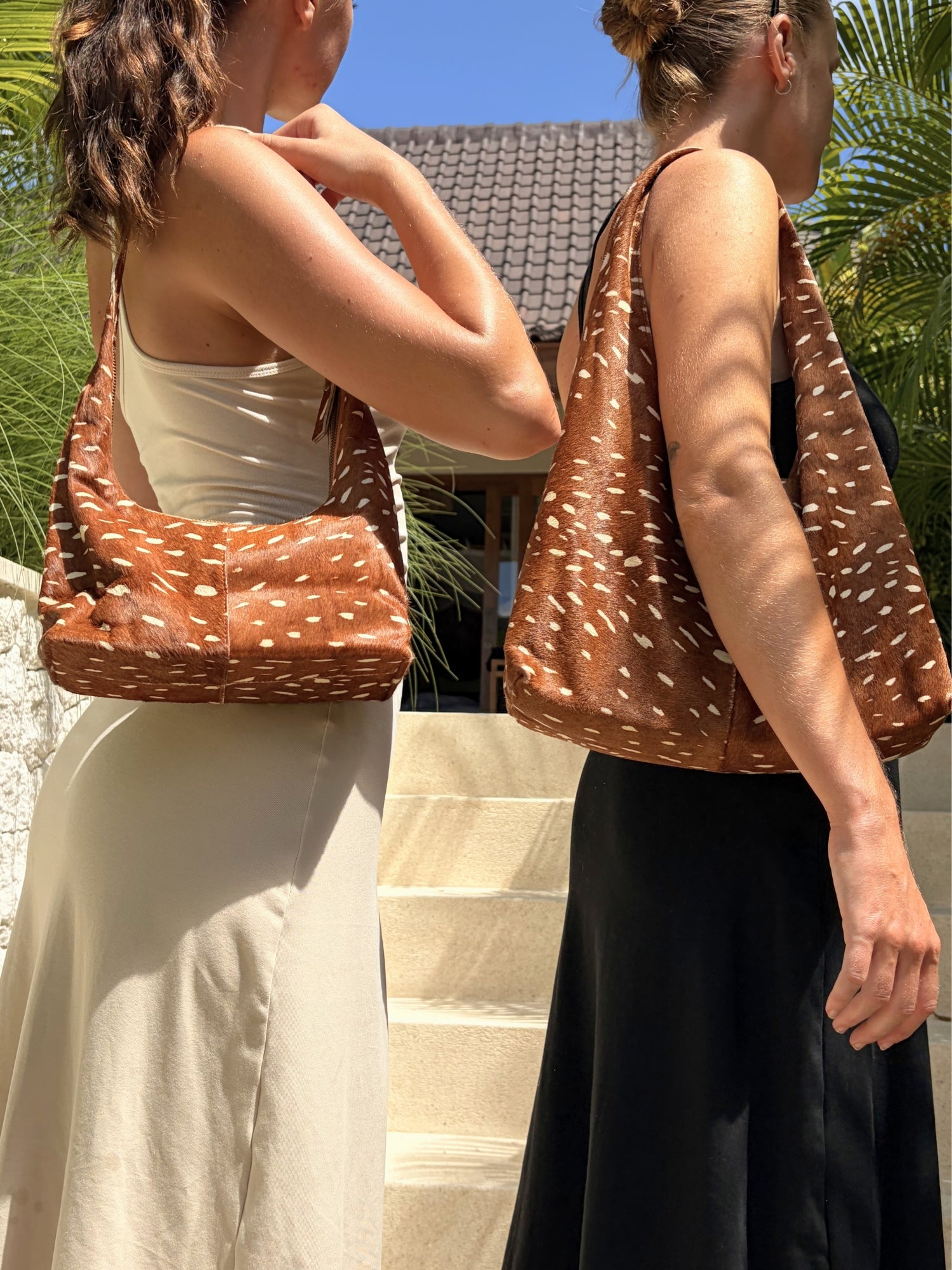 Two women carrying brown bambi patterned handbags in bali.